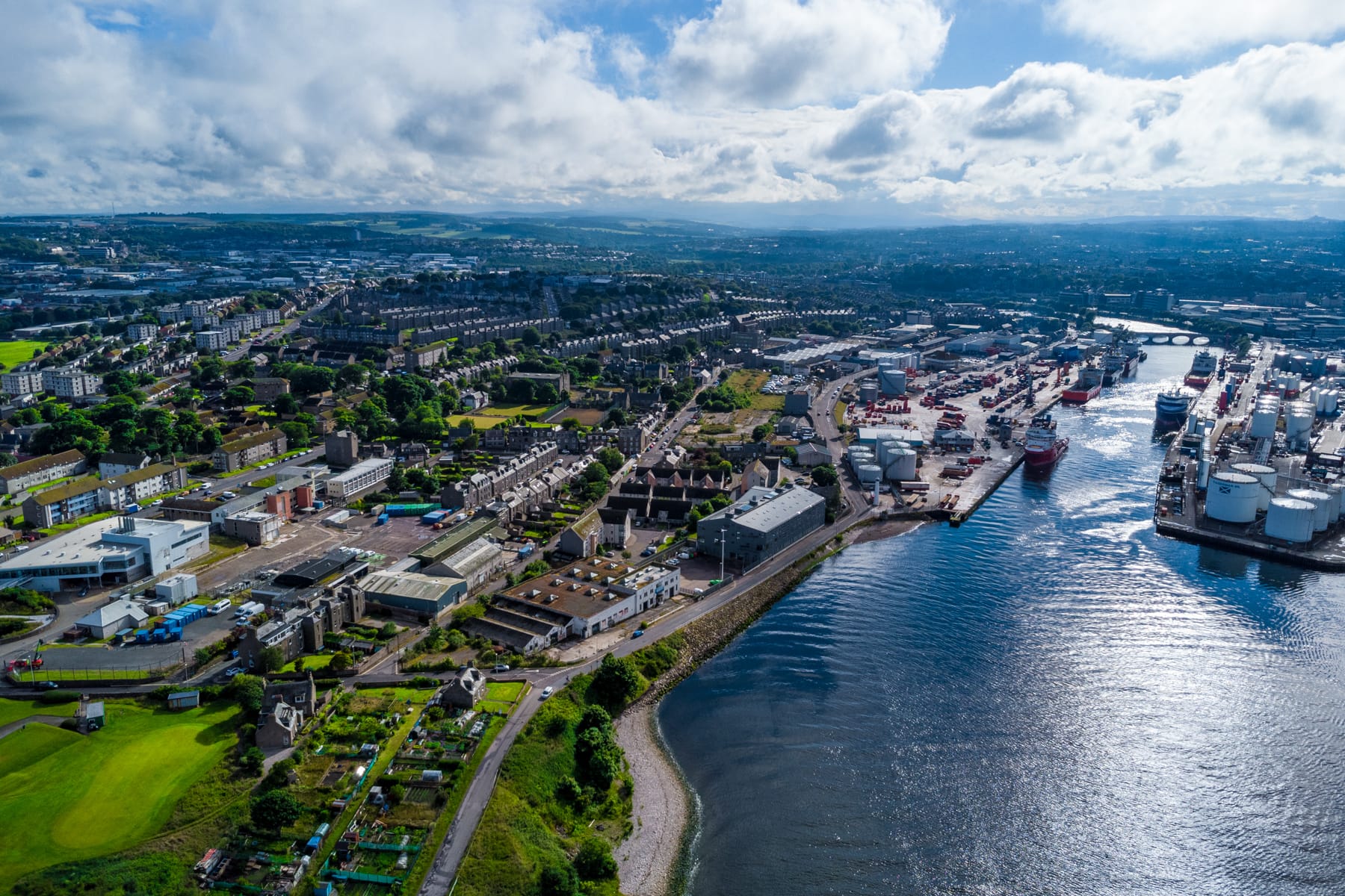Aerial view of Aberdeen Harbour with Torry on the left. The River Dee, ships, industrial docks, and residential areas are visible on the right.