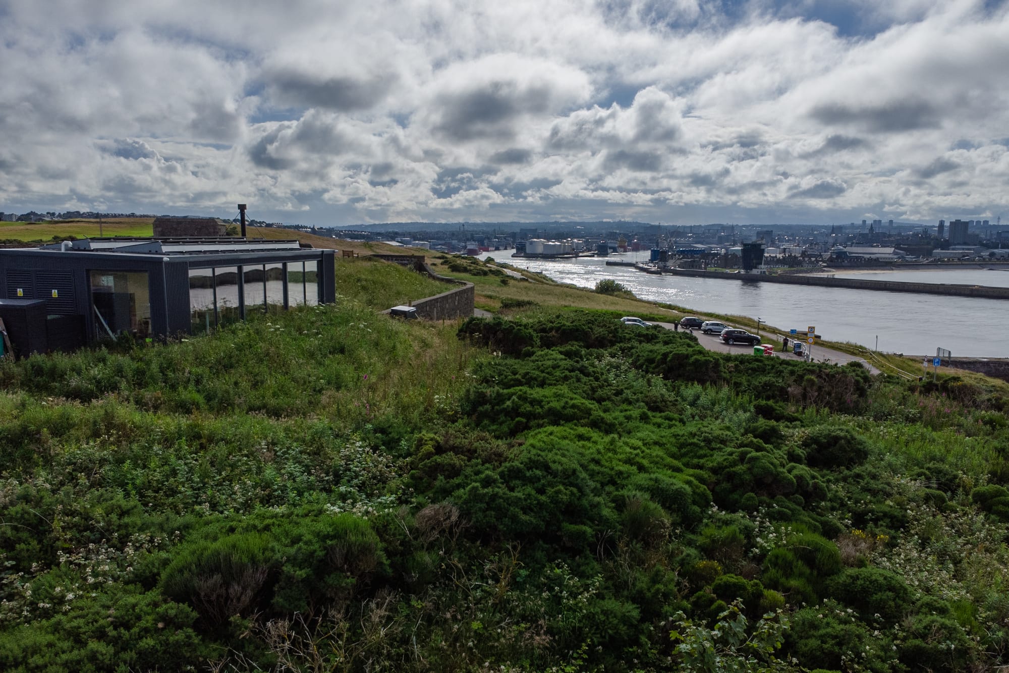 Greyhope Bay Centre on the left, with Aberdeen Harbour visible in the background under a cloudy sky.