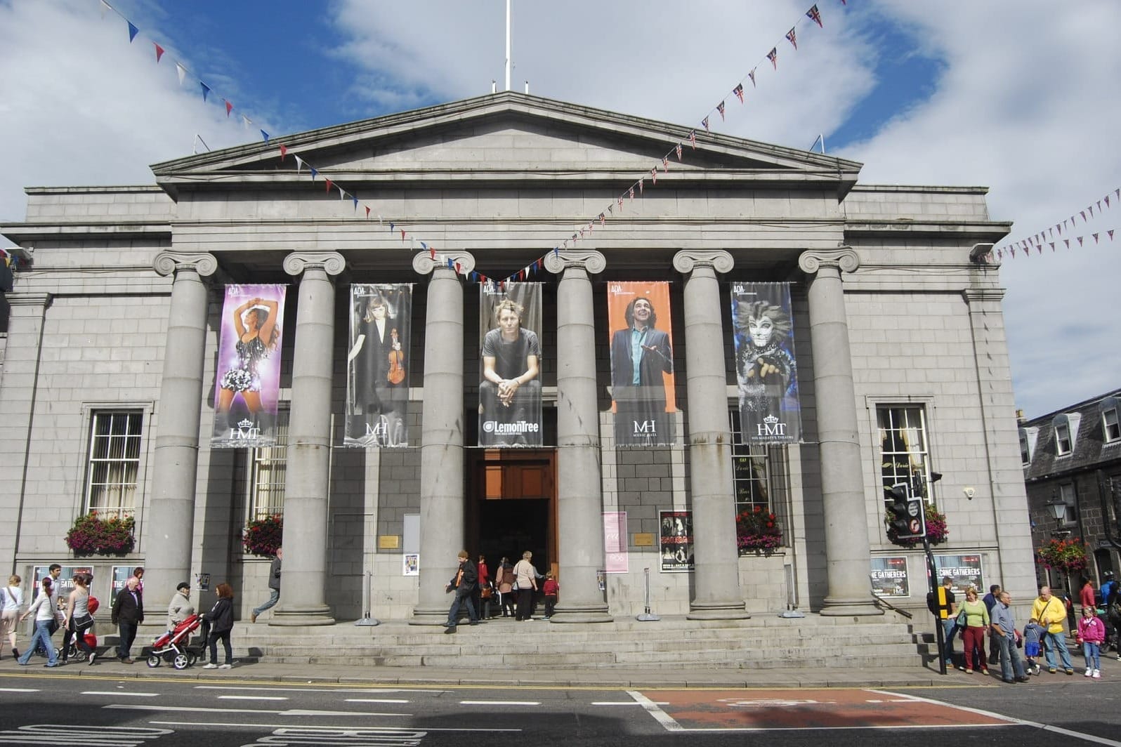 People outside Aberdeen Music Hall with banners hanging from its stone columns
