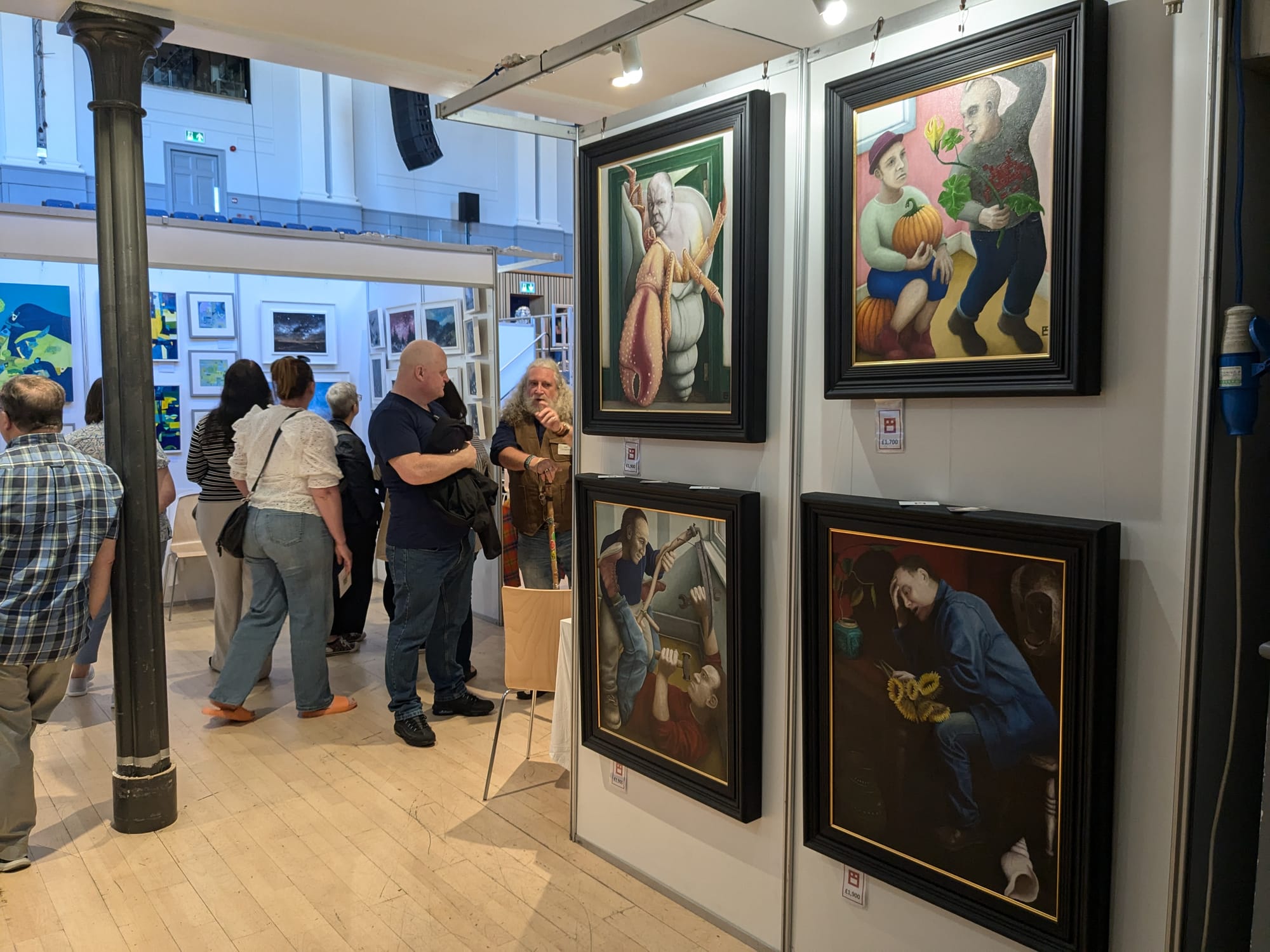 Visitors browse colourful paintings and framed works at Aberdeen Art Fair in a bright indoor venue.