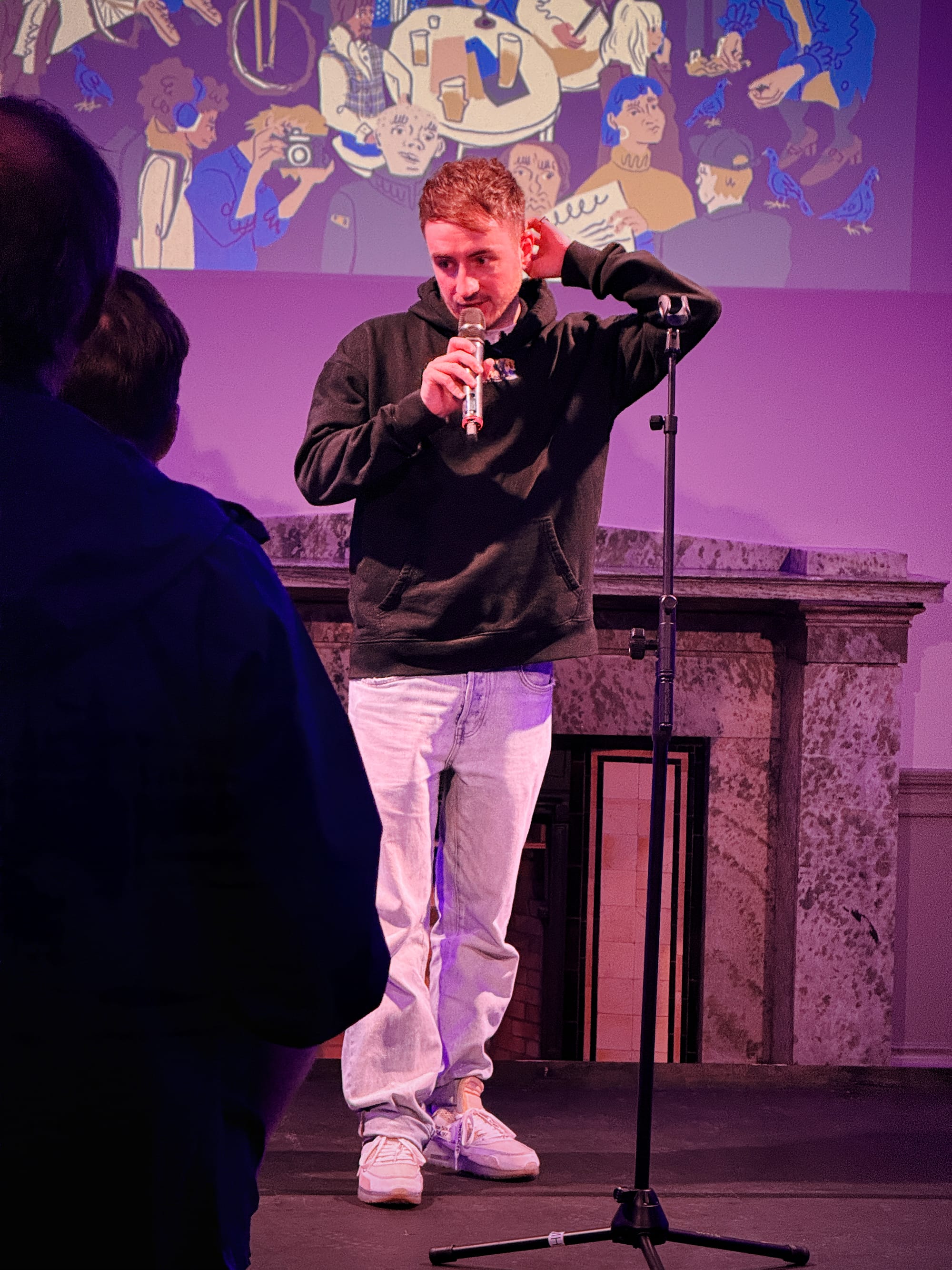 Vagrant Real Estate on stage with microphone, illustrated backdrop behind