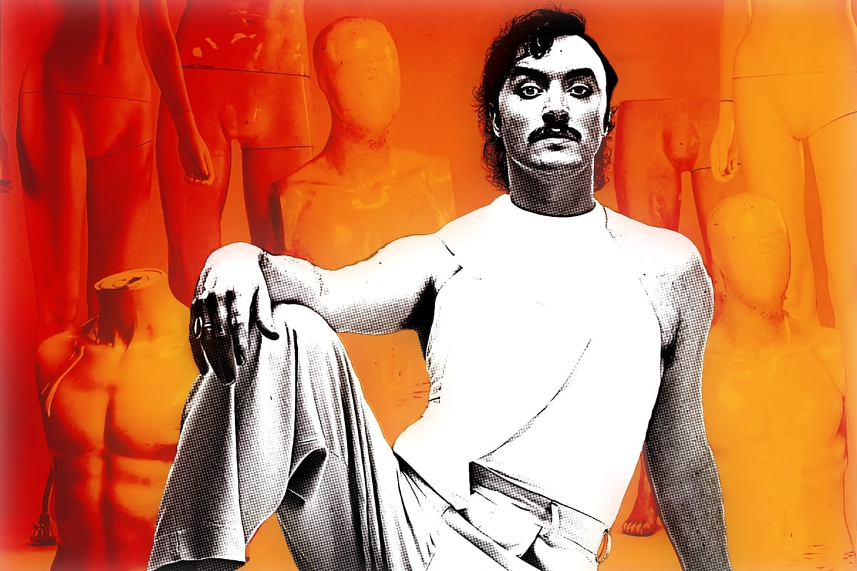 Dan Wye poses confidently in a white outfit against a backdrop of orange mannequins and shadows