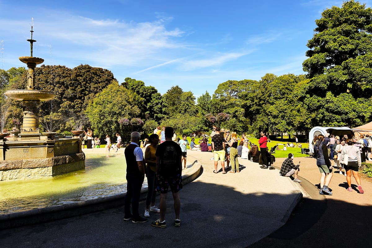 People gather near the granite fountain in Victoria Park, featured in the new family-friendly walking trail.