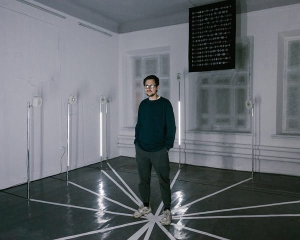 In the photo, artist Andrey Chugunov stands in the centre of a stark white room that’s part of an art installation. The floor