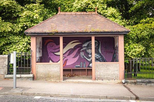 A mural by KMG and Hera on a bus stop beside Westburn Park features a figure with a spray can and an abstract bird.