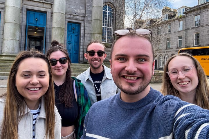 Five smiling members of A TO Z Theatre Company taking a selfie outside Aberdeen Arts Centre