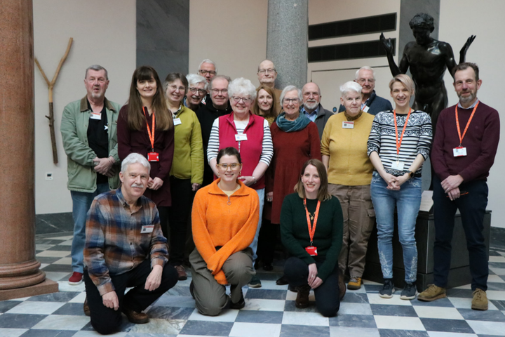 Group of AAGM volunteers smiling in the sculpture hall at Aberdeen Art Gallery.