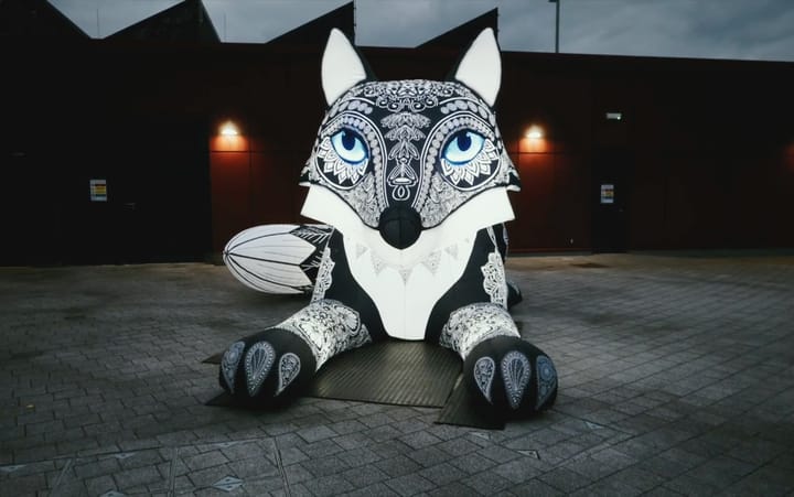 Large inflatable fox sculpture with black and white mandala patterns at night