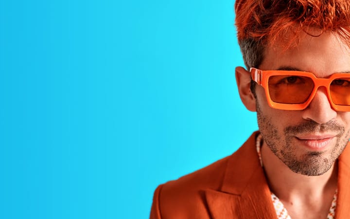 Ivo Graham in orange sunglasses and jacket with dyed orange hair.